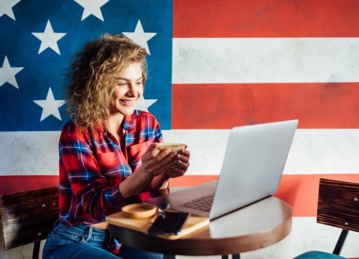 Young female entrepreneur working on her laptop with the USA flag in the background