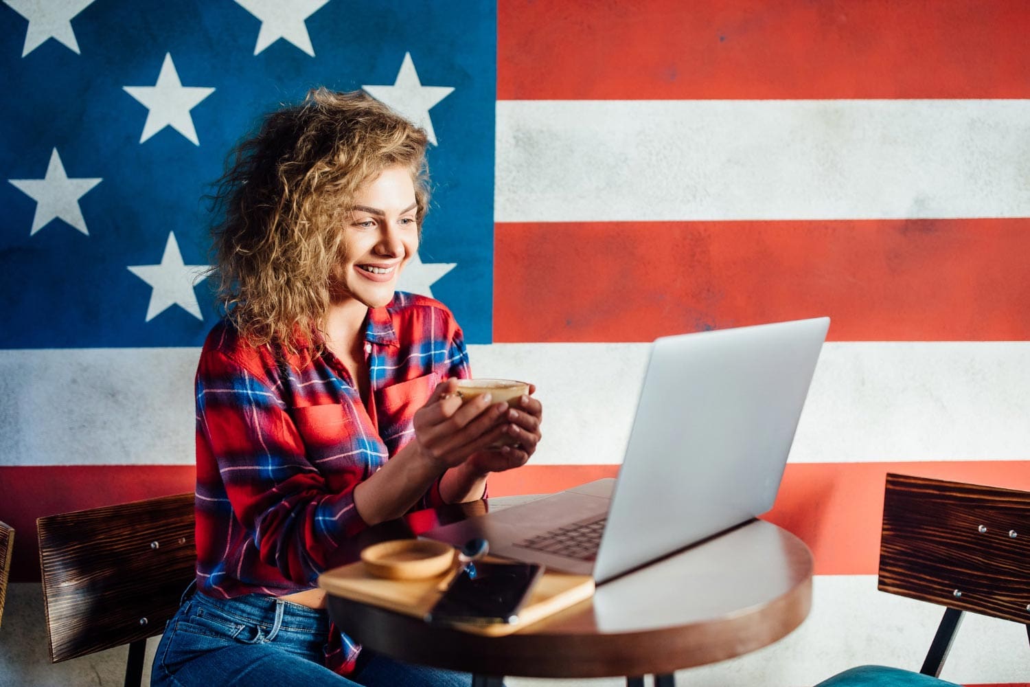 Young female entrepreneur working on her laptop with the USA flag in the background