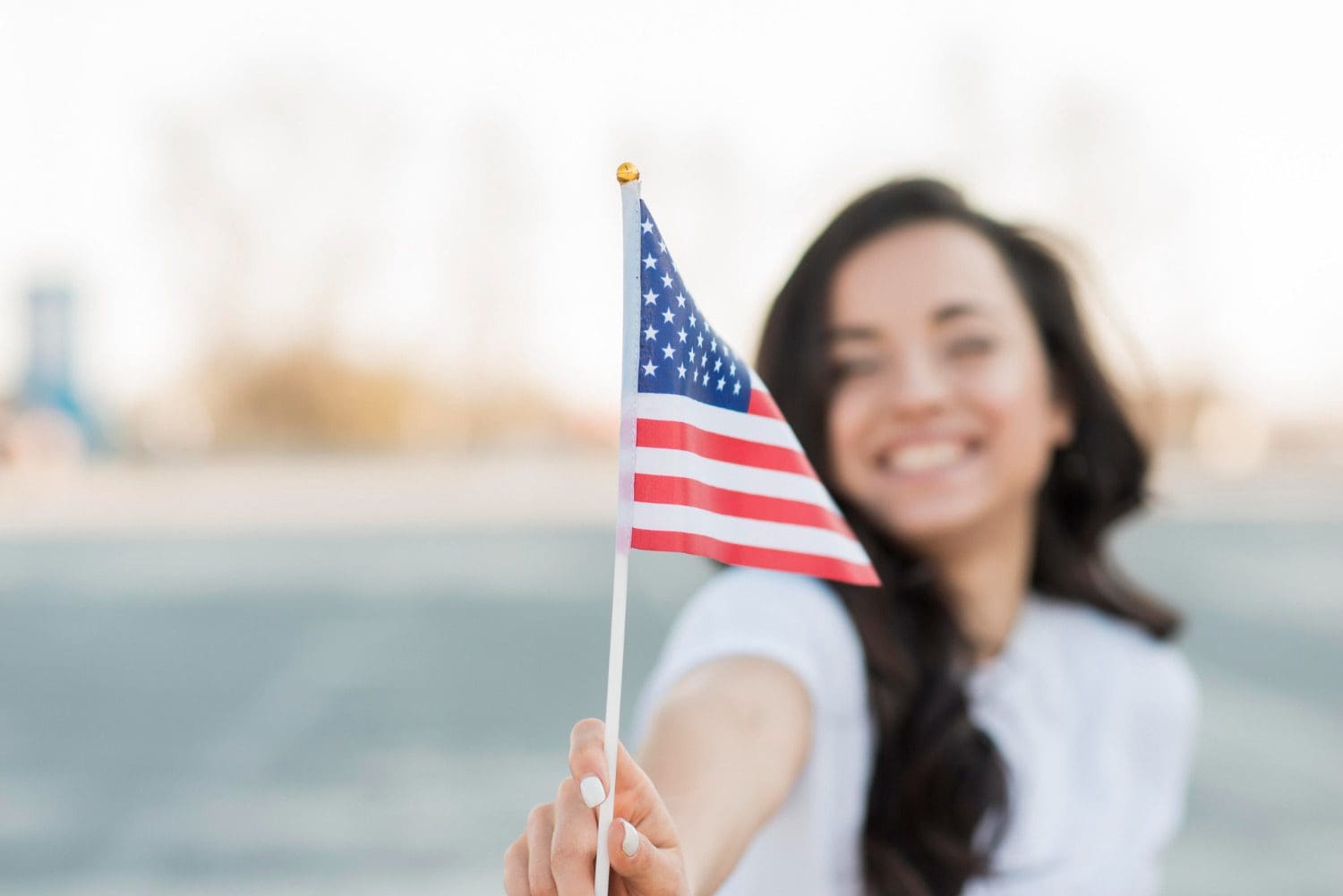 Close-up of a casually dressed businesswoman holding a USA flag and smiling