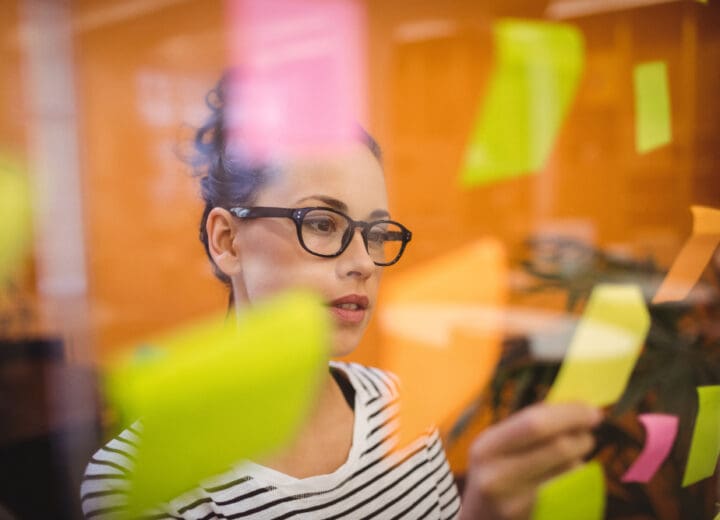 Female startup executive reviewing sticky notes filled with ideas