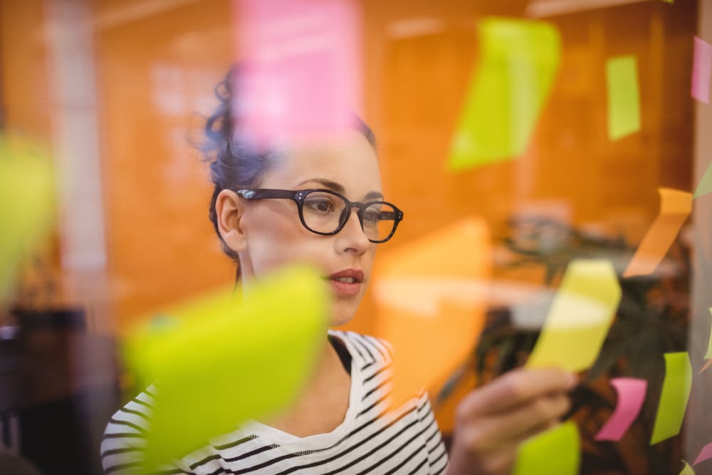 Female startup executive reviewing sticky notes filled with ideas