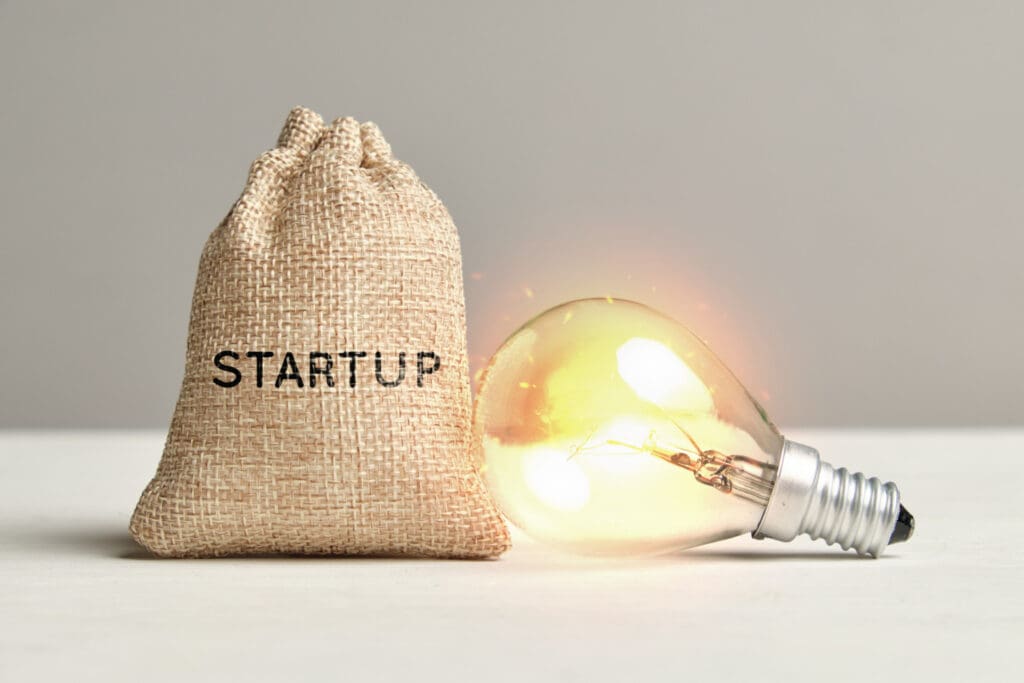 Startup concept with a glowing light bulb and a bag of money.